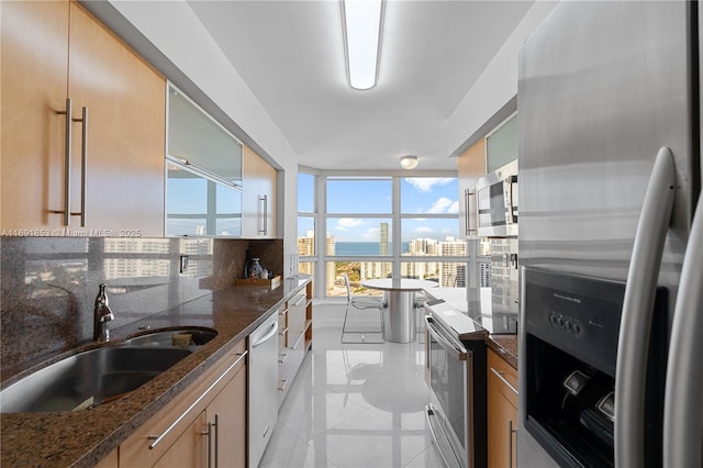 kitchen with backsplash, sink, dark stone countertops, light tile patterned floors, and stainless steel appliances