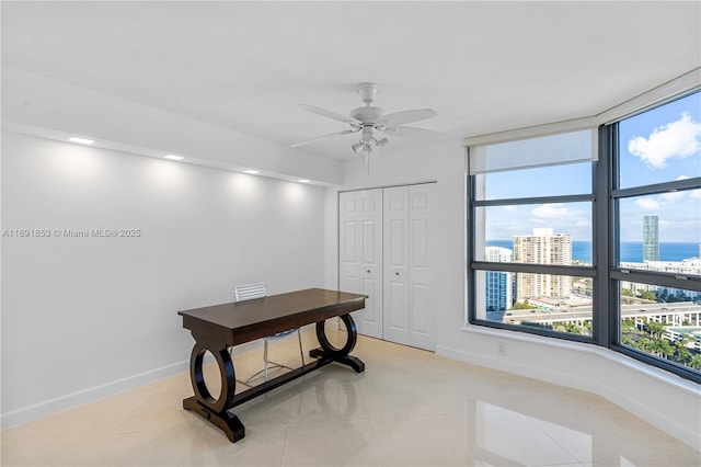 home office with ceiling fan, a water view, and light tile patterned floors