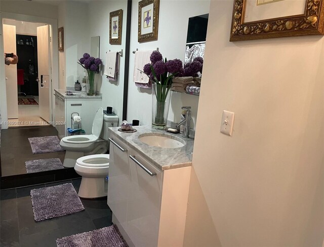 bathroom with toilet, vanity, a bidet, and tile patterned floors