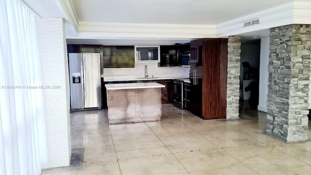 kitchen with stainless steel fridge with ice dispenser, sink, black electric range, and decorative columns