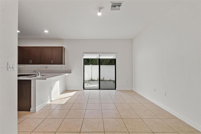 kitchen with dark brown cabinetry, light tile patterned flooring, and sink