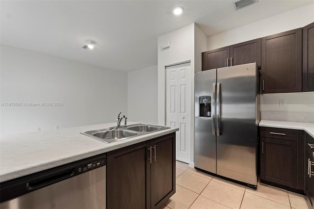 kitchen with stainless steel appliances, dark brown cabinets, light tile patterned floors, and sink