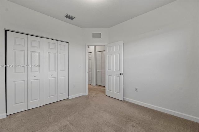 unfurnished bedroom featuring a closet and light colored carpet