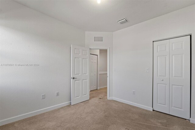 unfurnished bedroom featuring a closet and light colored carpet