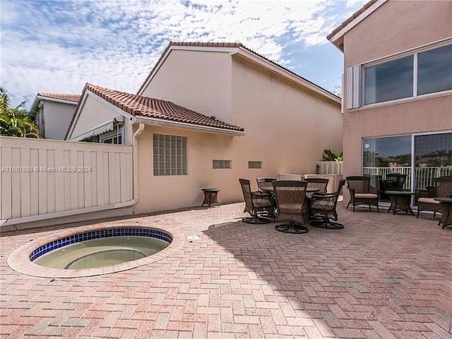 back of house with a patio area and an in ground hot tub