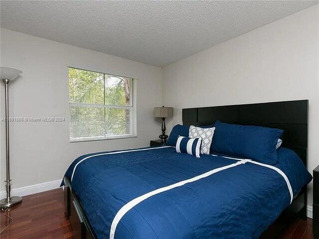 bedroom with a textured ceiling and dark hardwood / wood-style floors