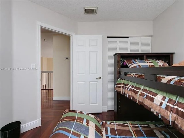 bedroom with dark wood-type flooring, a textured ceiling, and a closet