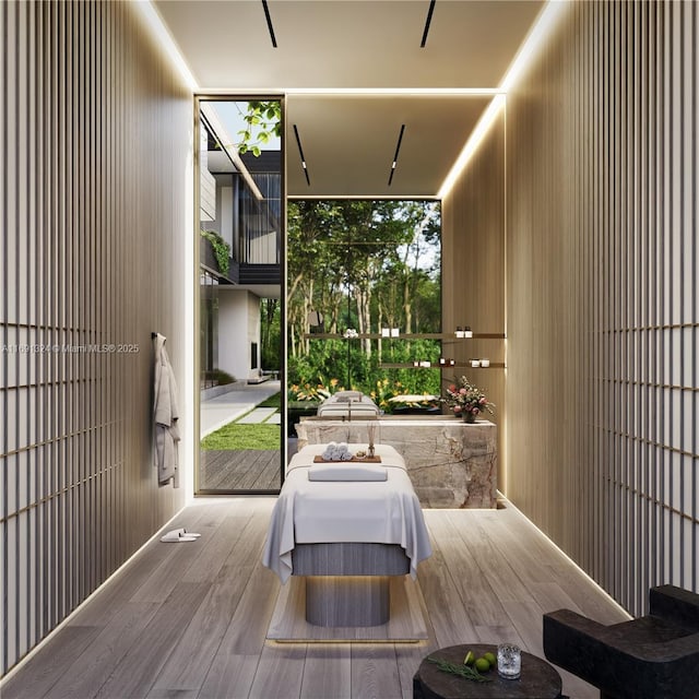 bedroom with a wall of windows, wood walls, and light hardwood / wood-style floors