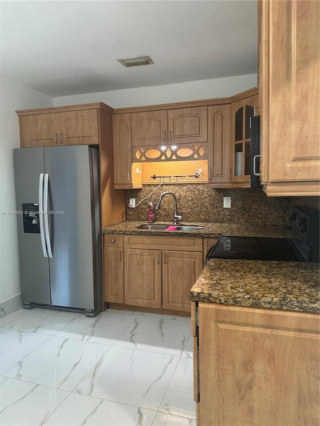 kitchen with sink, stainless steel refrigerator with ice dispenser, black range with electric cooktop, and dark stone counters