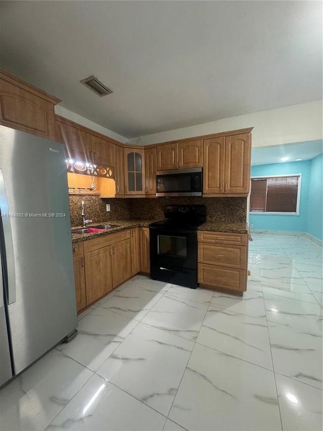 kitchen featuring backsplash, sink, dark stone counters, and stainless steel appliances