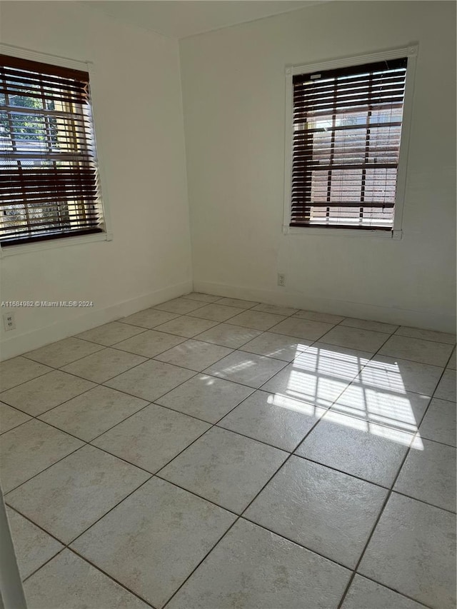 empty room featuring a wealth of natural light and light tile patterned floors