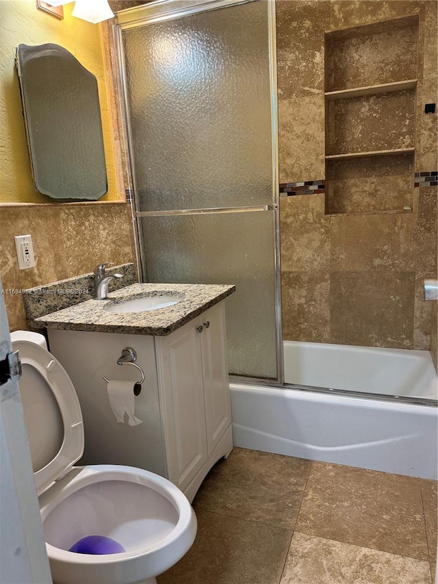 full bathroom with combined bath / shower with glass door, vanity, and toilet