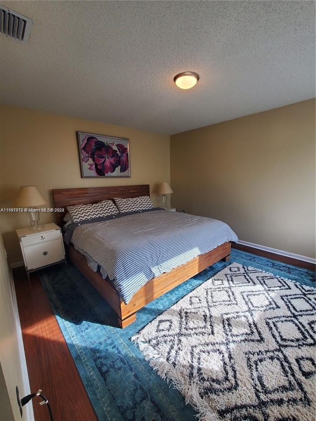 bedroom with dark hardwood / wood-style flooring and a textured ceiling