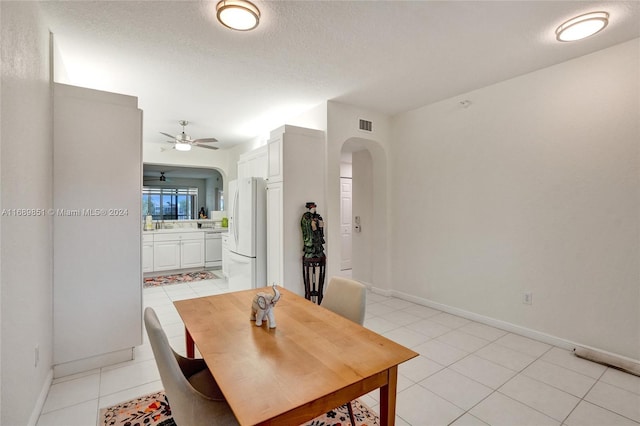 tiled dining space with ceiling fan and a textured ceiling