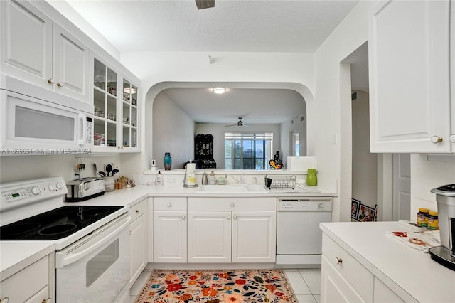 kitchen with white appliances, a textured ceiling, sink, light tile patterned floors, and white cabinetry