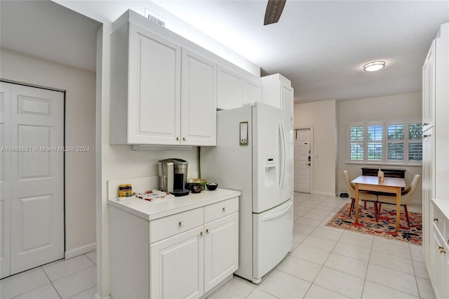 kitchen featuring white fridge with ice dispenser, white cabinets, light tile patterned flooring, and a textured ceiling