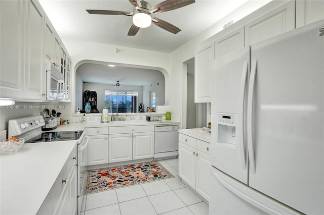 kitchen featuring white appliances, sink, light tile patterned floors, a textured ceiling, and white cabinetry