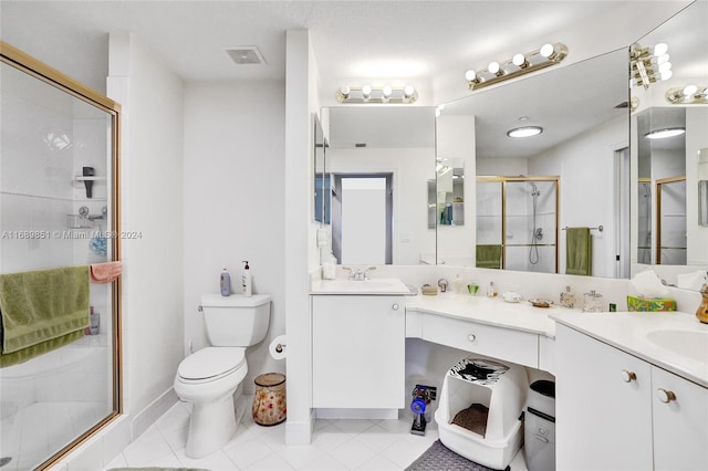 bathroom with tile patterned flooring, vanity, toilet, and a shower with door