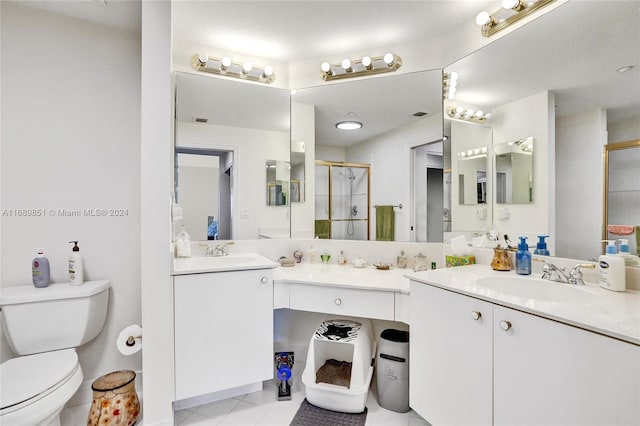 bathroom featuring tile patterned floors, vanity, toilet, and a shower with shower door