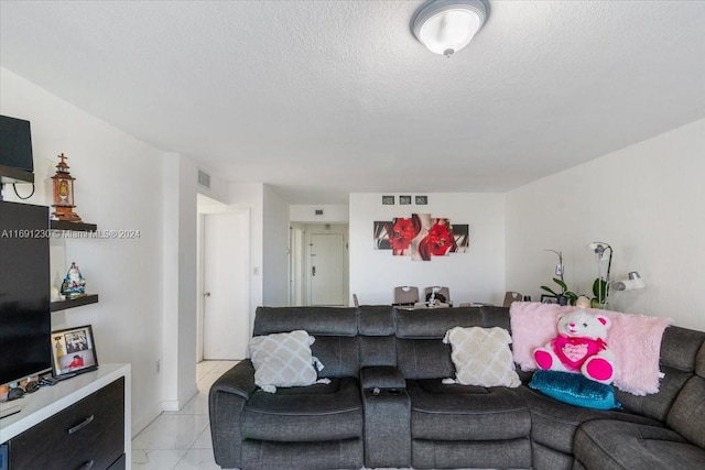 living room with a textured ceiling and light tile patterned floors