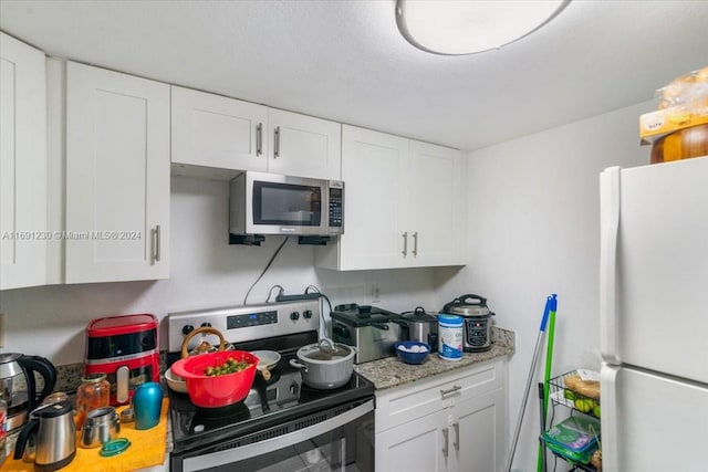 kitchen featuring light stone countertops, white cabinets, and stainless steel appliances