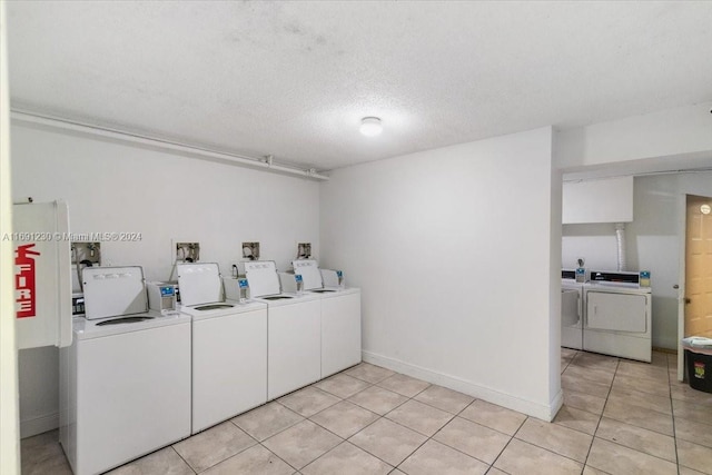 laundry area featuring independent washer and dryer, light tile patterned floors, and a textured ceiling