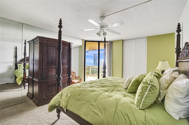 carpeted bedroom featuring a textured ceiling, access to outside, ceiling fan, a wall of windows, and a closet