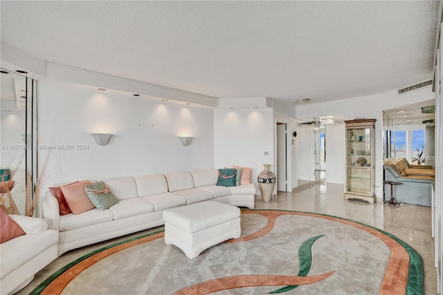 living room with light tile patterned floors, a textured ceiling, and ceiling fan