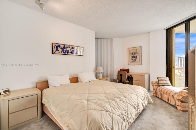 carpeted bedroom with a textured ceiling, access to outside, and floor to ceiling windows