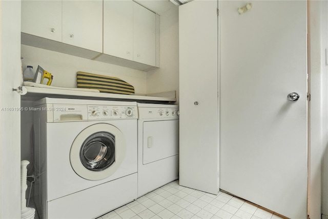 clothes washing area with cabinets, light tile patterned flooring, and washing machine and clothes dryer