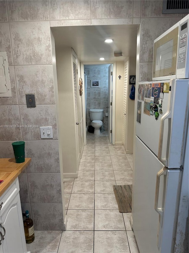 bathroom with vanity, tile patterned floors, toilet, and tile walls