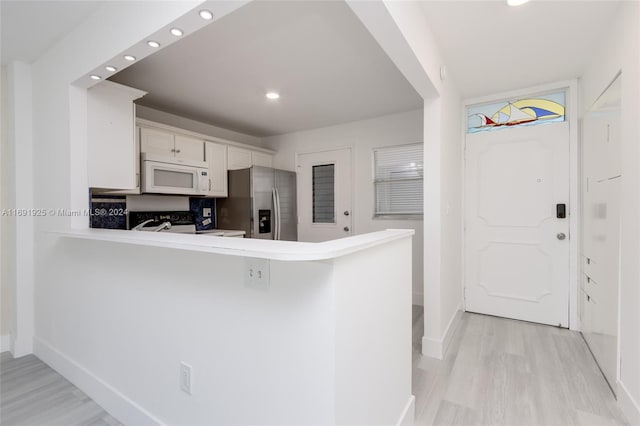 kitchen with white cabinetry, kitchen peninsula, light hardwood / wood-style floors, and stainless steel appliances