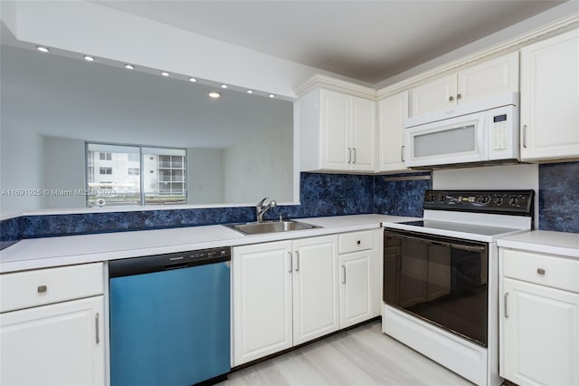 kitchen featuring sink, backsplash, white cabinetry, light wood-type flooring, and white appliances