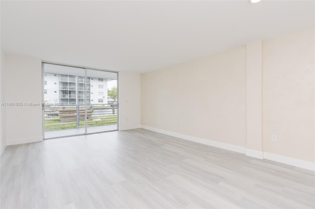 empty room with light hardwood / wood-style floors and floor to ceiling windows