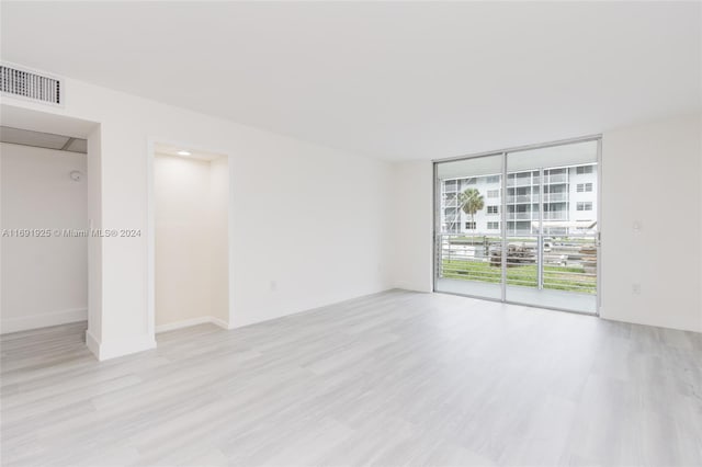 spare room with a wall of windows and light hardwood / wood-style floors