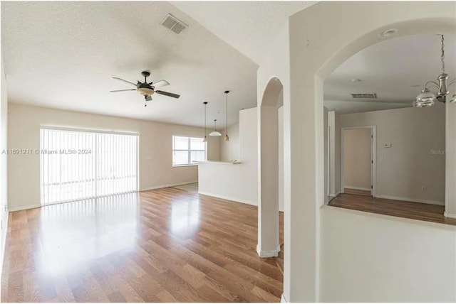 spare room featuring wood-type flooring, a textured ceiling, and ceiling fan with notable chandelier