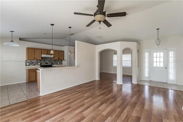 unfurnished living room with wood-type flooring, ceiling fan, and vaulted ceiling