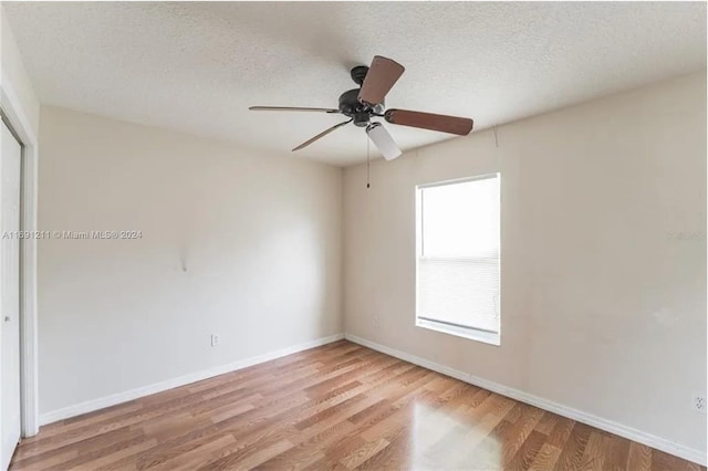 spare room featuring light wood-type flooring, a textured ceiling, and ceiling fan