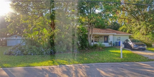 view of front of home featuring a front yard, an outbuilding, and a garage