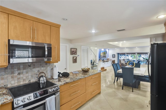 kitchen featuring light stone countertops, appliances with stainless steel finishes, backsplash, and light tile patterned floors