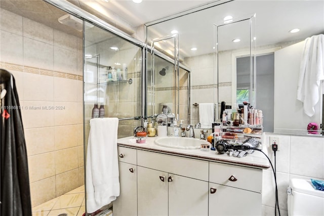 bathroom with tile patterned floors, toilet, tile walls, an enclosed shower, and vanity