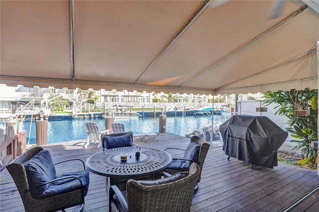 wooden terrace featuring a dock, a water view, and grilling area