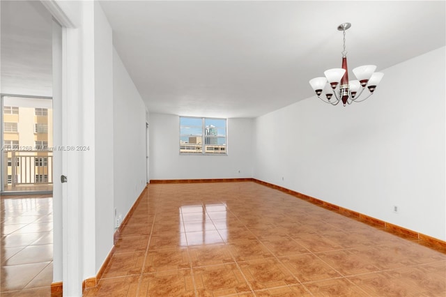 tiled spare room with an inviting chandelier