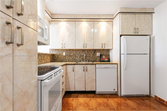 kitchen featuring white appliances, dark stone countertops, sink, and backsplash