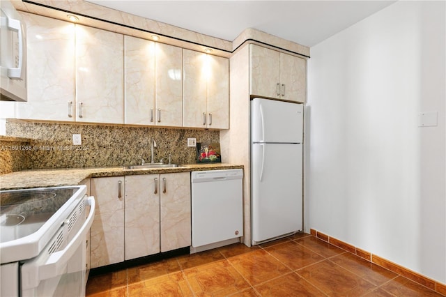 kitchen featuring backsplash, light stone countertops, sink, tile patterned flooring, and white appliances