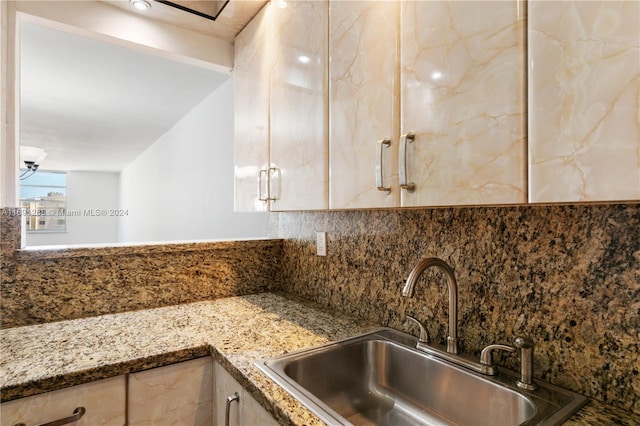 kitchen featuring dark stone counters, sink, and tasteful backsplash