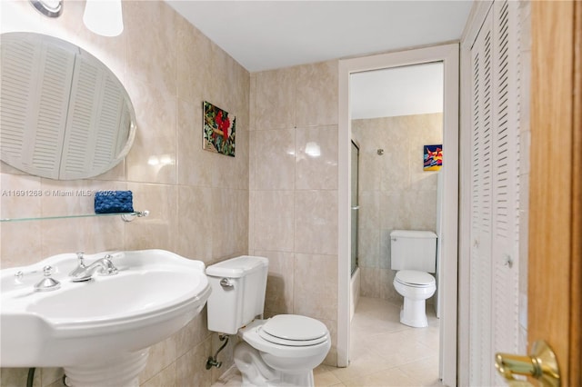 full bathroom with tile walls, toilet, shower / bath combination with glass door, and tile patterned floors