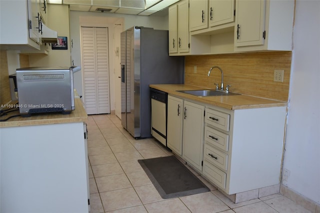 kitchen with white dishwasher, light tile patterned flooring, sink, and tasteful backsplash