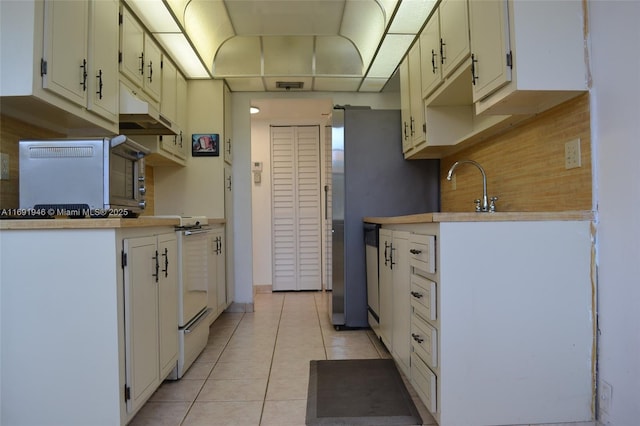 kitchen featuring light tile patterned floors, white cabinetry, and sink