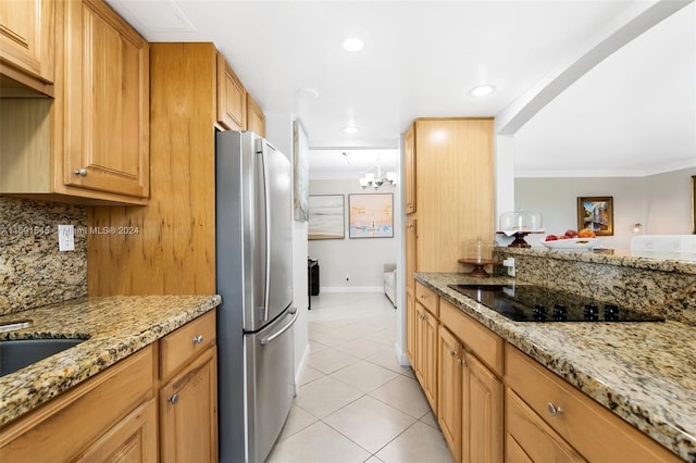 kitchen with light stone countertops, black electric cooktop, crown molding, and stainless steel fridge